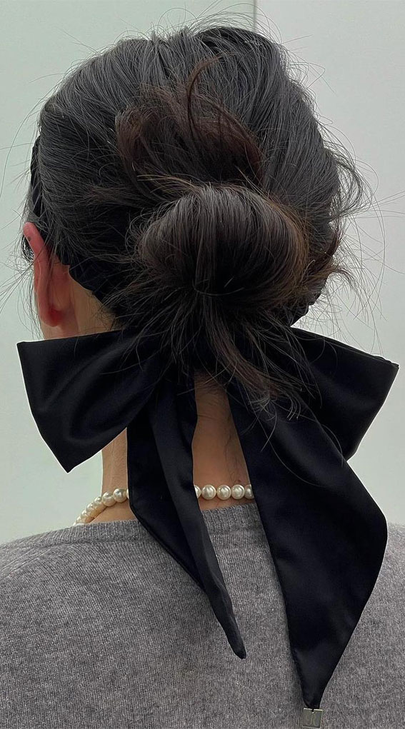 A Trendy Collection of Hairstyles Adorned with Chic Bows : Messy Low Bun with Oversized Black Bow