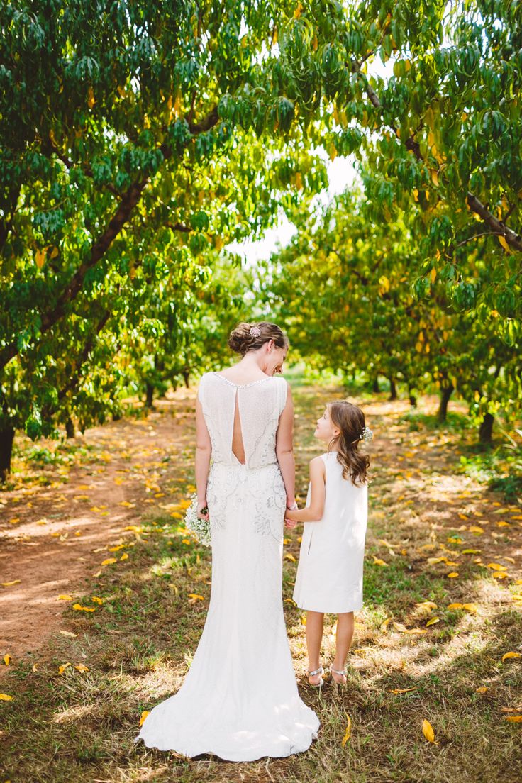 bride and flower girl in white Wedding in The Peach Orchard | Photography : marymargaretsmith.com | https://www.fabmood.com/a-cozy-fall-wedding-in-the-peach-orchard #peach #fallwedding