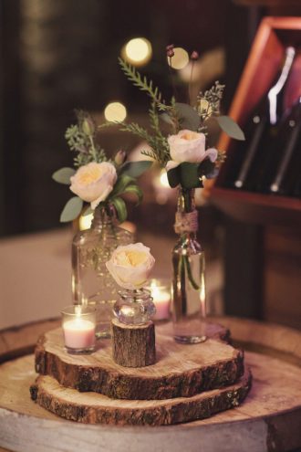 Roses filled in brown bottles with twine wrapped on wooden slice as rustic wedding centerpice,rustic centerieces,bottle centerpieces ,wine bottle centerpieces,wooden slice centerpieces #weddingcenterpieces #rusticweddingcenterpieces