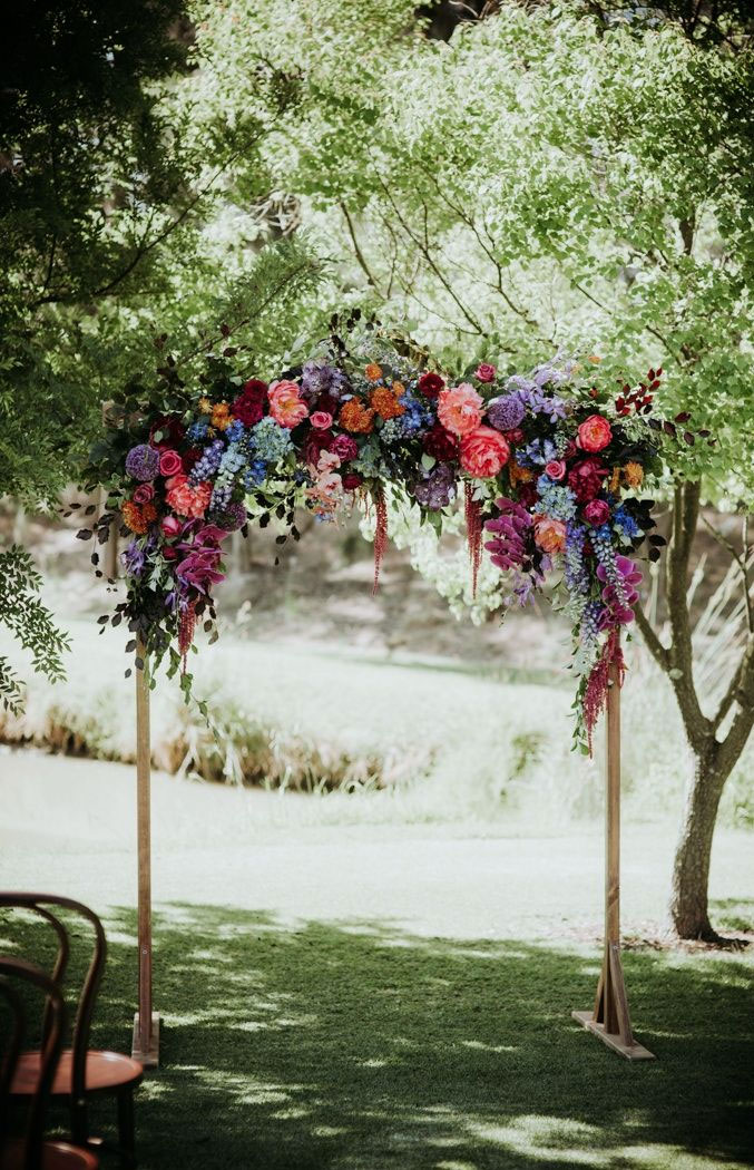 7 Wedding Arches That Will Instantly Upgrade Your Ceremony - Colorful flowers decorated wedding arch - Fall wedding ideas #fallwedding #autumnwedding